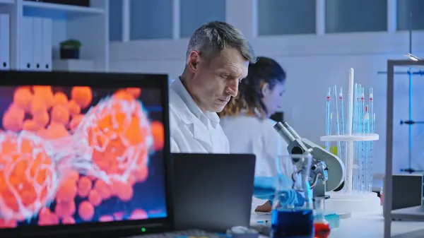 Viroloji bilimadamı mikroskop altında enfeksiyon hücrelerini araştırıyor.