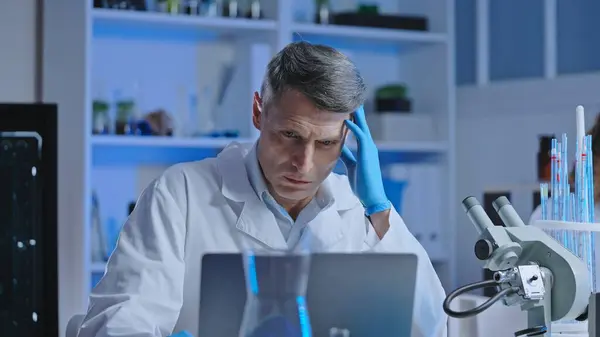 Puzzled medical lab scientist checking virus research progress on computer