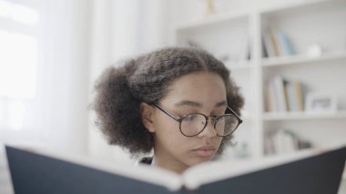 Gözlüklü zeki üniversite öğrencisi kitap okuyor, ödev yapıyor, akademik stres, eğitim