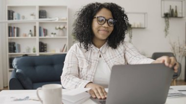 Mutlu siyah kadın işini bitirir ve dizüstü bilgisayarını, uzaktan kumandayı, serbest çalışanı kapatır.