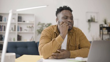 Afrikalı Amerikalı bir adam video izliyor ya da kulaklığı kablosuz kulaklıkla online konferans görüşmesi yapıyor, yeni cihazın keyfini çıkarıyor.