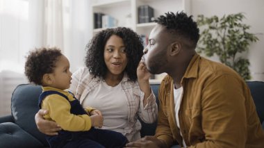 Küçük çocuk ebeveynlerinin oynayışına dikkatle bakıyor ve onu eğlendirmeye çalışıyor.