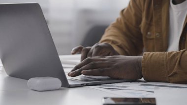 Evdeki dizüstü bilgisayarda daktilo eden Afrikalı Amerikalı adamın yakın çekimi, uzaktan çalışma, serbest çalışma.