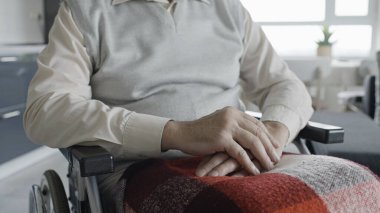 Engelli bir adam tekerlekli sandalyede oturuyor, el ele tutuşuyor, rehabilitasyon oluyor.