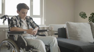 Özürlü ergen çocuk akıllı telefon uygulaması kullanarak arkadaşlarıyla internetten sohbet ediyor.