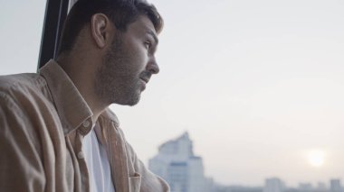 Camdan dışarı bakan düşünceli genç adam, önemli bir karar veriyor.