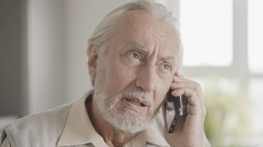Gri saçlı adam telefonla konuşuyor, tıbbi danışmanlık alıyor, doktordan tavsiye istiyor.