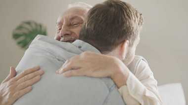 Mutlu büyük baba ve yetişkin oğul kanepede sarılıyor, aile sevgisi ve desteği