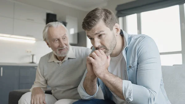 Büyük baba üzgün yetişkin oğlunu destekliyor, güvenilir aile ilişkisi.
