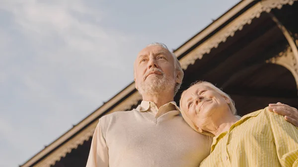 Retired couple hugging and looking into distance, happy marriage, social security