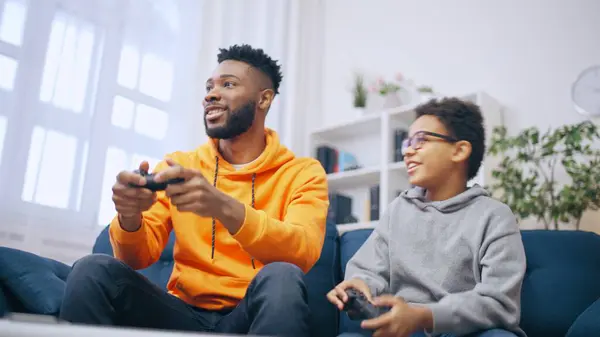 Older African American brother showing little one how to play video game, leisure