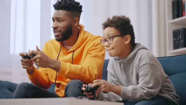 Excited elder and junior brothers playing video games together, having fun
