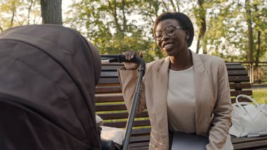 Gülümseyen anne parkta bankta otururken bebeğine hayranlık duyuyor.