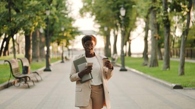 Başarılı iş kadını akıllı telefondan mesaj okuyor ve parkta kahve içiyor.