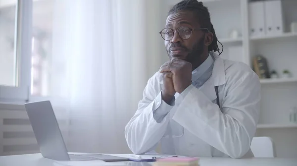 Thoughtful black therapist thinking about patient\'s treatment strategy, concerned about results