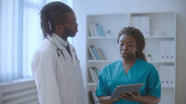 African American nurse and therapist talking at work, discussing patients\' test results
