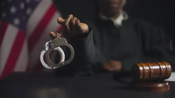 Siyahi kadın yargıç kamerada kelepçe gösteriyor, suçlulara ceza, hukuk