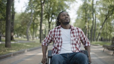 Hastane parkında tekerlekli sandalye kullanan Afro-Amerikalı bir adam.