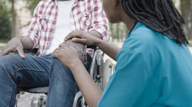 Tekerlekli sandalyedeki erkek hastayı destekleyen kadın hemşire, iletişim, iyileşme