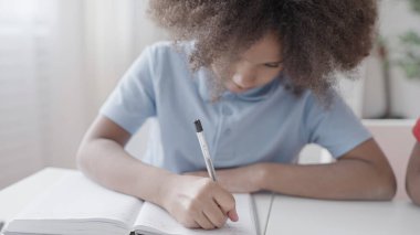 Küçük kız evde ders çalışıyor, matematik problemleri yazıyor, evde eğitim görüyor.