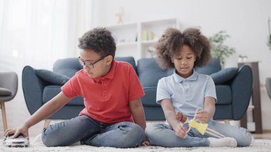 Afrikalı Amerikalı erkek ve kız evde oyuncak araba ve bebekle oynuyorlar, eğleniyorlar.