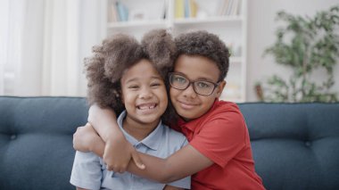 Mutlu Afro-Amerikan çocukları kamerada sarılıp gülümsüyor, en iyi arkadaşlar destekliyor.