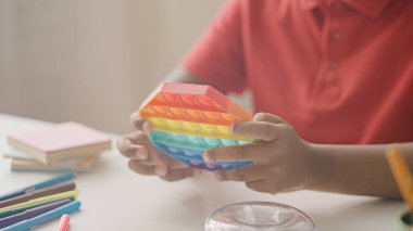 Çocuğun elleri Pop it ile oynuyor. Duyusal stres atlama oyuncağıyla eğleniyor.