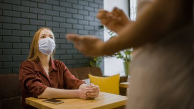 Koruyucu maskeli bir kadın restoranda, horeca işinde, salgın hastalıkta düzen sağlıyor.