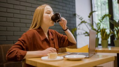 Diz üstü bilgisayarda işini bitiren ve kahve içen kız öğrenci, serbest meslek