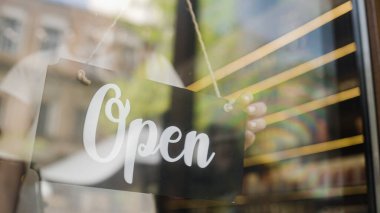 Garson açık kapı tabelası asıyor, restoran ya da kahve dükkanı ziyaretçiler için hazır.