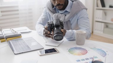 Afrikalı Amerikalı bir fotoğrafçı yeni fotoğraf makinesine hafıza kartı yerleştiriyor.