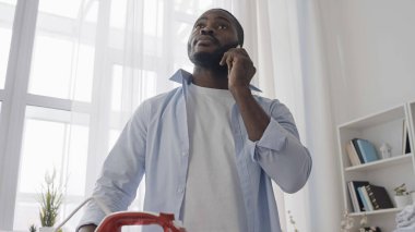 Genç adam telefonda konuşurken kızgın ütüyle kıyafetleri mahvediyor.