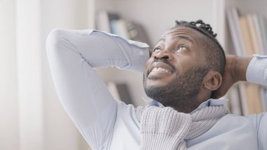 Mutlu siyahi adam koltuğunda oturuyor ve yukarı bakıyor, hayal kuruyor.