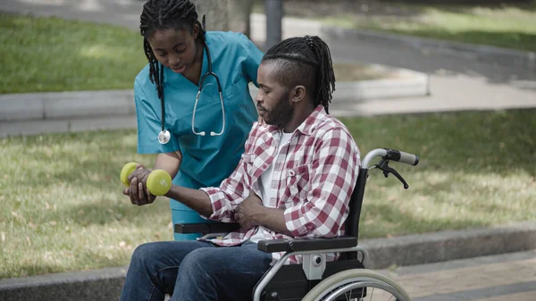 Rehabilitation doctor helping patient in wheelchair to exercise for recovery