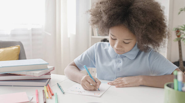 Школьница с вьющимися волосами готовит праздничную открытку, рисует в школе, праздники