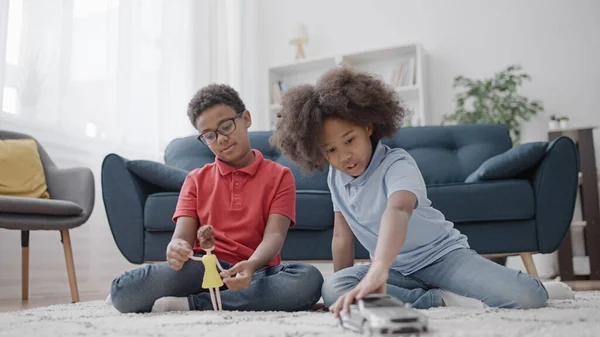 Black girl and boy playing with a doll and a car, breaking gender stereotyping in toys