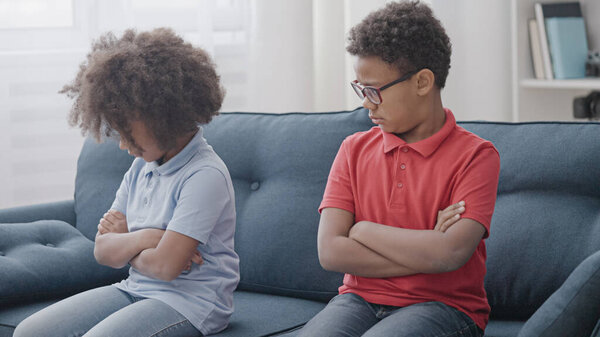 Offended kids sitting on couch, conflict between siblings, family relations