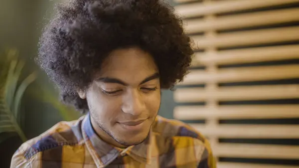 stock image Smiling mixed race man with afro hair sitting in cafe, listening to his friend, night out