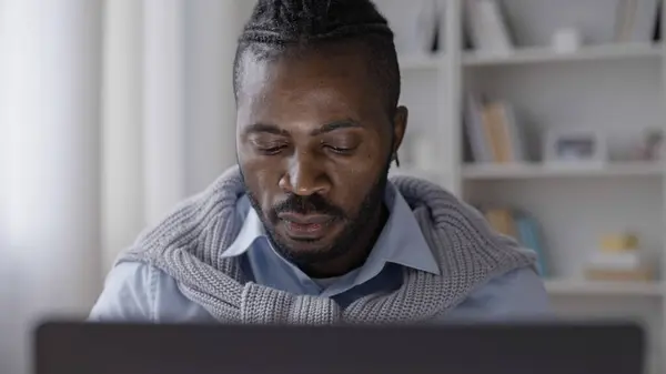 African American man software developer working on laptop at cozy home office