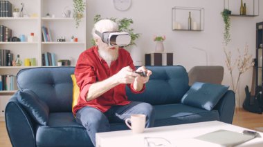 A man in his 60s engages in a video game using VR glasses, experiencing virtual reality entertainment