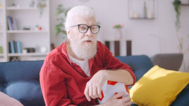 A man in his 60s immersed into a football game on TV, an excited soccer fan waiting for the score