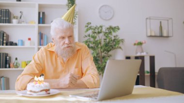 Senior man joyfully accepts birthday greetings from his family via an online video call