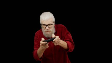Senior man plays a video game with a joystick on a black background, enjoying his leisure time