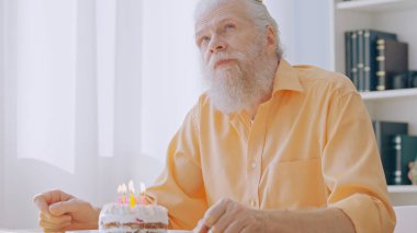 A concentrated grandpa appears thoughtful as he makes a wish on his birthday