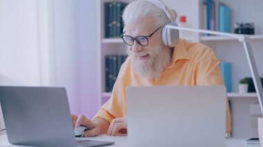 Contemporary grandpa streams himself playing video games online, feeling youthful and embracing his role as a vlogger