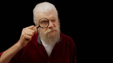 Funny senior man peers through a magnifying glass, embodying a sense of question and scrutiny