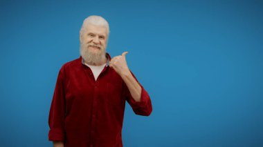 Senior man points at the space beside him, suggesting a place for advertisement or promotion