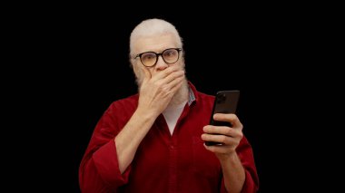 Senior man scrolls through his smartphone and encounters shocking news, displaying complete surprise