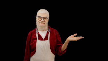 Smiling man in an apron points at an empty space on a black background, perfect for placing text