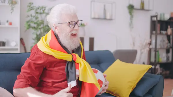 Close-up of an excited elder supporting the German football team while watching the game at home